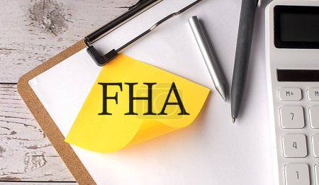 Palabra FHA en amarillo pegajoso con calculadora, pluma y portapapeles