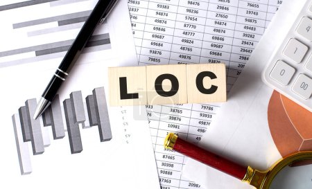 Foto de LOC - Línea de texto de crédito sobre un bloque de madera sobre fondo gráfico con lápiz y lupa - Imagen libre de derechos