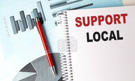 Téléchargez les photos : SUPPORT LOCAL texte sur ordinateur portable avec stylo sur fond de graphique - en image libre de droit