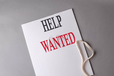 Photo for HELP WANTED text on a white folder on grey background - Royalty Free Image