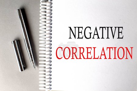 Photo for NEGATIVE CORRELATION text on notebook with pen on grey background - Royalty Free Image