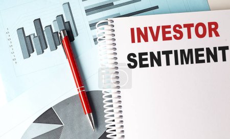 INVESTOR SENTIMENT text on notebook with pen on a chart background