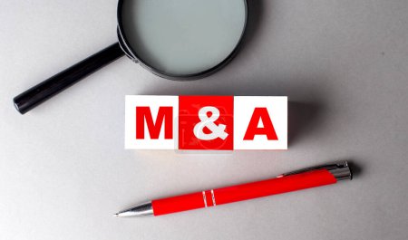 M and A word on a wooden cubes with pen and magnifier