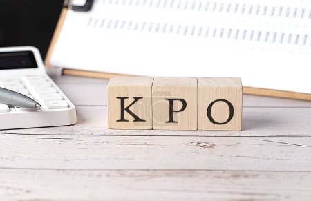 KPO-Wort auf Holzblock mit Klemmbrett und Taschenrechner