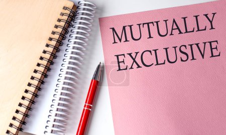 Photo for MUTUALLY EXCLUSIVE word on pink paper with office tools on white background - Royalty Free Image