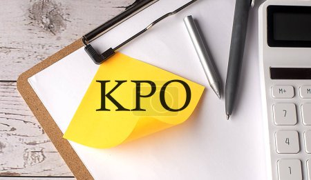 Téléchargez les photos : Mot KPO sur jaune collant avec calculatrice, stylo et presse-papiers - en image libre de droit