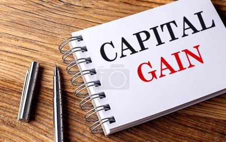Photo for CAPITAL GAIN text on a notebook with pen on wooden background - Royalty Free Image