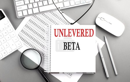 Photo for UNLEVERED BETA text on a notepad on chart with keyboard and calculator on grey background - Royalty Free Image