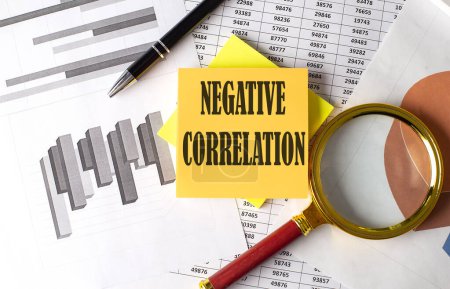 Photo for NEGATIVE CORRELATION text on sticky on the graph background with pen and magnifier - Royalty Free Image