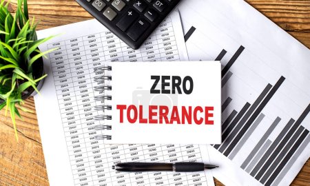 Photo for ZERO TOLERANCE text on notebook with chart and calculator - Royalty Free Image