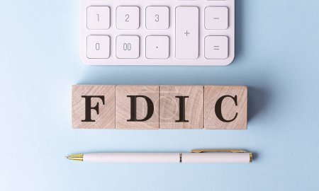 Photo for FDIC on a wooden cubes with pen and calculator, financial concept - Royalty Free Image