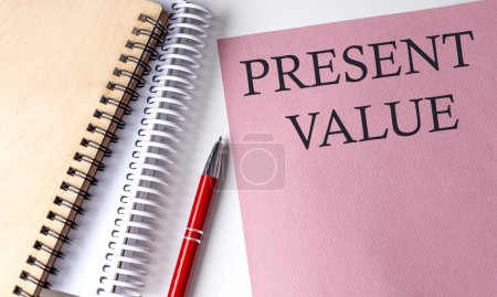 Foto de VALOR PRESENTE palabra sobre papel rosa con herramientas de oficina sobre fondo blanco - Imagen libre de derechos
