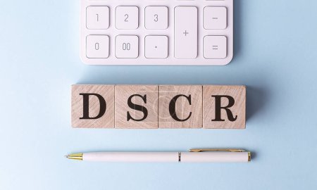 DSCR en cubos de madera con pluma y calculadora, concepto financiero