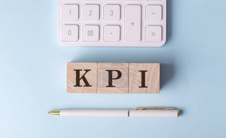 Téléchargez les photos : KPI sur un cube en bois avec stylo et calculatrice, concept financier - en image libre de droit