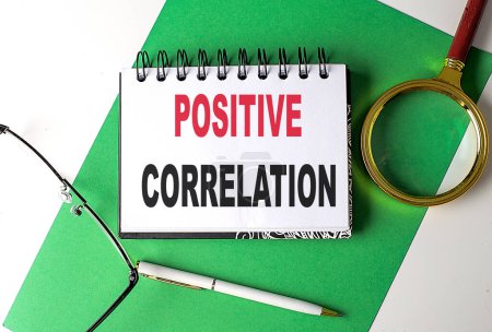 Photo for POSITIVE CORRELATION text on a notebook on green paper - Royalty Free Image