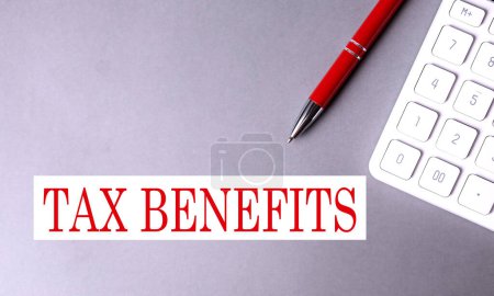 TAX BENEFITS text written on gray background with pen and calculator