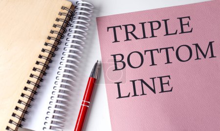 TRIPLE BOTTOM LINE Wort auf rosa Papier mit Bürowerkzeugen auf weißem Hintergrund