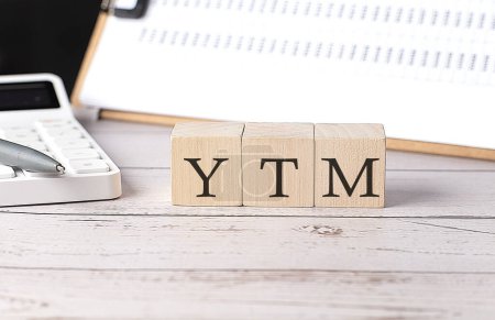 YTM Wort auf Holzblock mit Klemmbrett und Taschenrechner