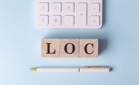 Foto de LOC en cubos de madera con pluma y calculadora, concepto financiero - Imagen libre de derechos