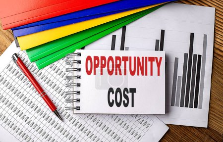 OPPORTUNITY COST text on notebook with pen, folder on a chart background