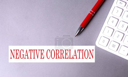 Photo for NEGATIVE CORRELATION text written on gray background with pen and calculator - Royalty Free Image