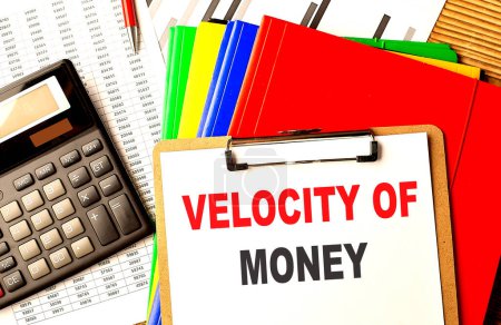 VELOCITY OF MONEY text written on a paper clipboard with chart and calculator