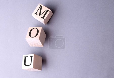 Word MOU on a wooden block on the grey background