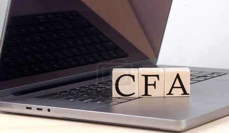 CFA-Wort auf einem Holzklotz am Laptop, Geschäftskonzept