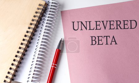 UnLEVERED BETA palabra sobre papel rosa con herramientas de oficina sobre fondo blanco