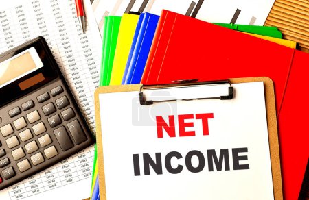 NET INCOME text written on a paper clipboard with chart and calculator