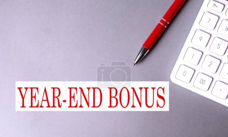 YEAR-END BONUS text written on gray background with pen and calculator