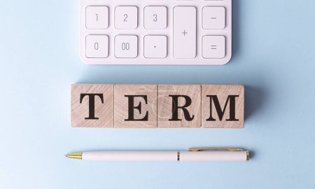 TERM on a wooden cubes with pen and calculator, financial concept