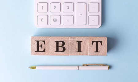EBIT auf Holzwürfel mit Stift und Taschenrechner, Finanzkonzept