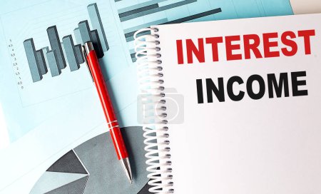 INTEREST INCOME text on notebook with pen on a chart background