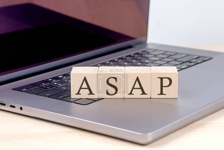 ASAP word on a wooden block on laptop, business concept