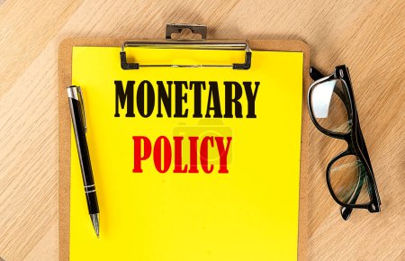 MONETARY POLICY text on ayellow paper on wooden background