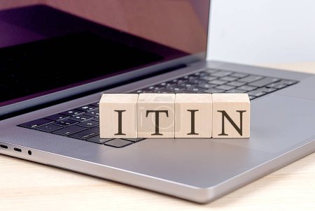 ITIN word on a wooden block on laptop, business concept