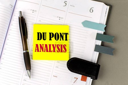 DU PONT ANALYSIS palabra en amarillo pegajoso con herramientas de oficina en planificador diario