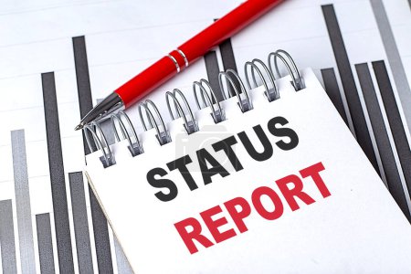 STATUS REPORT text written on a notebook with pen on chart