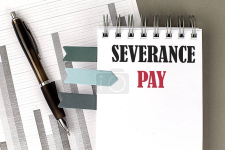 SEVERANCE Pay Text auf einem Notizbuch mit Stift, Taschenrechner und Diagramm auf grauem Hintergrund