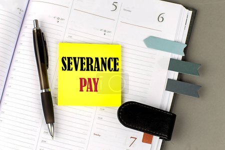 SEVERANCE PAY word on yellow sticky with office tools on daily planner