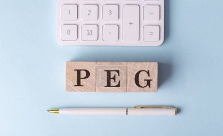 PEG auf Holzwürfel mit Stift und Taschenrechner, Finanzkonzept