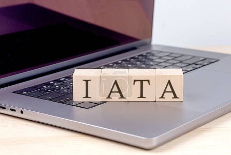 IATA-Wort auf einem Holzklotz am Laptop, Geschäftskonzept