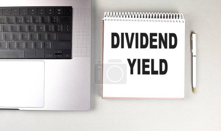 DIVIDEND YIELD text on a notebook with laptop and pen