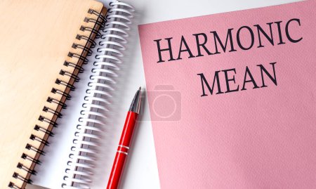 HARMONIC MEAN Text auf rosa Papier mit Notizbuch.