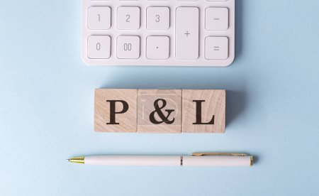P AND L word on wooden block with pen and calculator on a blue background 
