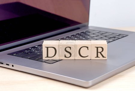 Téléchargez les photos : Mot DSCR sur le bloc en bois sur ordinateur portable. - en image libre de droit