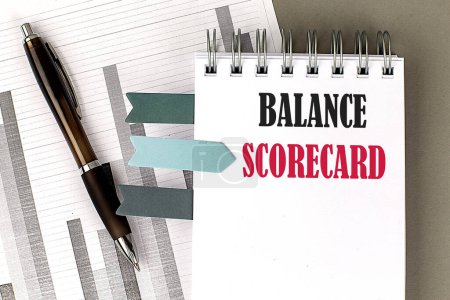 BALANCE SCORECARD text on the notebook with chart on gray background.