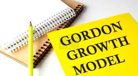 GORDON GROWTH MODEL texte sur un papier jaune avec cahiers. 