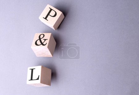P AND L word on wooden block on gray background 